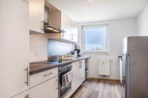 a kitchen with white cabinets and a stainless steel refrigerator at Ferienwohnung Krautsand in Drochtersen +21 photos