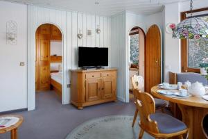 a living room with a television and a table with chairs at Oskar im Bärenhüsli in Titisee-Neustadt