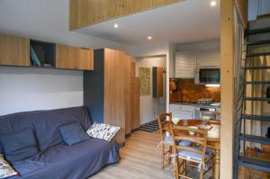 a living room with a couch and a table and a kitchen at Cosy Studio Mezzanine in Allevard
