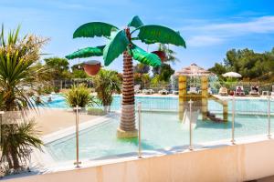 a pool at a resort with a palm tree at Mobil-Home Baia in Saint-Raphaël