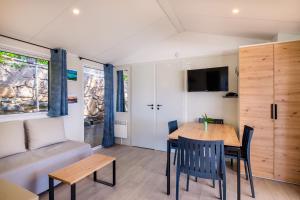 a dining room with a table and chairs and a couch at Mobil-Home Baia in Saint-Raphaël
