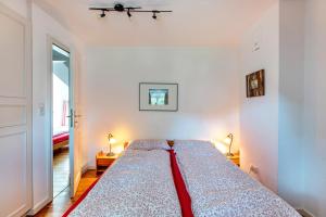 a bedroom with a bed with a red blanket on it at Skriiwers Hüüs in Alkersum