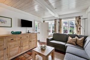 a living room with a couch and a tv at Skriiwers Hüüs in Alkersum
