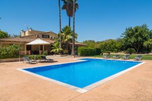 a swimming pool with chairs and a house at Es Caulls in Llubí