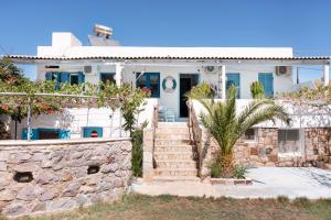 a white house with a stone wall and a palm tree at Beachfront Lampis Dolphin 4 in Skala +24 photos