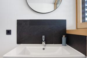 a bathroom sink with a round mirror above it at Ferienwohnung Böhler in Doren +16 photos