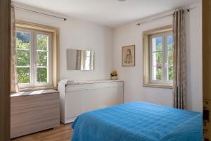 a bedroom with a blue bed and two windows at Villa Stanga in Sedico