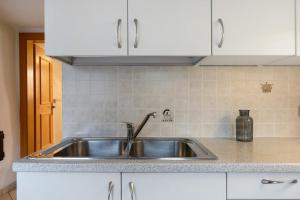 a stainless steel sink in a kitchen with white cabinets at Ferienhaus Leitner in Tires +68 photos