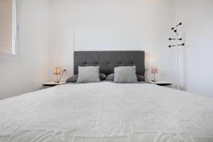a white bedroom with a large bed with two lamps at Casa Jable in Costa de Antigua