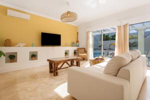 a living room with a white couch and a tv at Villa Ole Bahiazul-Private Jacuzzi in Corralejo