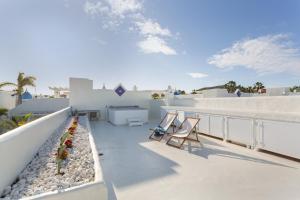 a balcony with chairs and a table on a building at Villa Ole Bahiazul-Private Jacuzzi in Corralejo