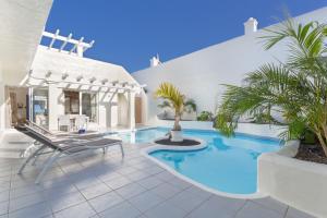 a villa with a swimming pool and a chair at Villa Ole Bahiazul-Private Jacuzzi in Corralejo