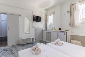 a white room with two beds and a tv at A Tinian Room 1 in Tinos