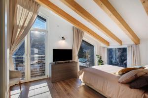 a bedroom with a bed and a tv and large windows at La Maison du Renard in Sarre