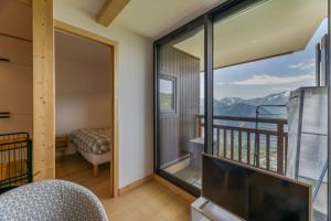 a room with a balcony with a view of the mountains at Appartement Alpe d'huez in LʼHuez