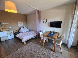 a bedroom with a desk and a bed and a table and chairs at Schwarzwald Heimat mit Pool, Sauna in Schönwald +19 photos