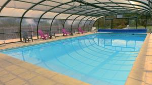 a swimming pool with purple chairs and a greenhouse at Domaine de Chante-Oiseau - 34 pers in Theil-Rabier +23 photos