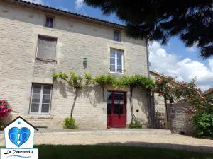 a stone house with a red door and flowers at Domaine de Chante-Oiseau - 34 pers in Theil-Rabier