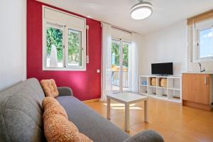 a living room with a gray couch and a red wall at Dorada Apartment Mar in Calafell