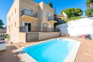 a villa with a swimming pool in front of a house at Dorada Apartment Mar in Calafell