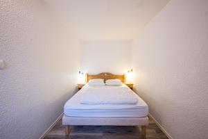 a bed in a small room with white walls at Résidence Les Bergers 71 in Valloire