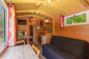 a living room with a couch in a tiny house at Roulotte insolite terrasse nature in Touët-sur-Var
