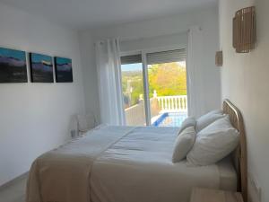 a white bedroom with a bed with pillows and a window at Villa Del Sol - Solo Familias 1819 in Jávea +36 photos