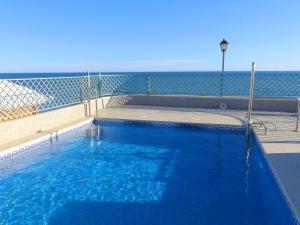 a blue swimming pool with the ocean in the background at Appartement Tesoro del Mar in Torrox Costa