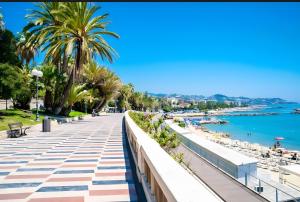 a walkway near the beach with palm trees and the water at Magia e Luce in Sanremo