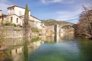 a bridge over a river in front of a building at Le Vigan, balcon, parking, animaux in Le Vigan