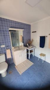 a blue tiled bathroom with a toilet and a sink at Finca El Carbayal in El Campo