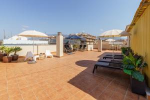 a patio with benches and umbrellas on a roof at Penthouse Victoria in Fuengirola