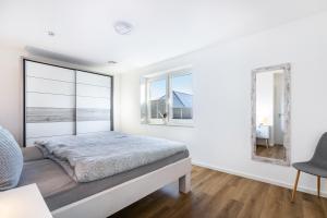 a white bedroom with a large bed and windows at Haus Luise in Bramstedtlund