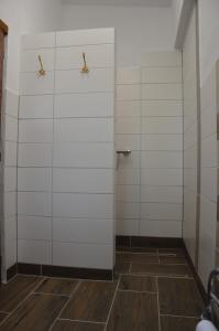 a bathroom with white tiled walls and wooden floors at Campingfass Bunge 1 in Krostitz