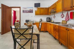a kitchen with wooden cabinets and a table with chairs at Casa Vacanza Da Gabry in Perdaxius
