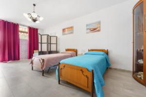a bedroom with two beds and purple curtains at Casa Vacanza Da Gabry in Perdaxius