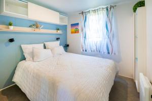 a bedroom with a white bed and a window at Camping Les Oyats in Seignosse +17 photos