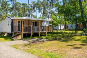 a tiny house with a porch and a deck at Camping Les Oyats in Seignosse
