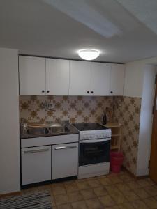 a kitchen with white cabinets and a stove and sink at Oberhöher Apt Talblick in San Pietro