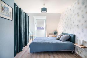a bedroom with a blue bed and green curtains at Gîte Ty Berniques in Pléneuf-Val-André +12 photos