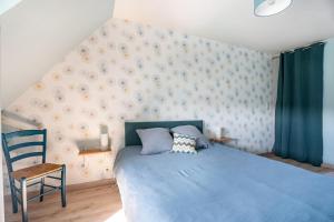 a bedroom with a blue bed and a chair at Gîte Ty Berniques in Pléneuf-Val-André