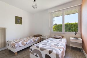 a bedroom with two beds and a window at Gîte de Mirabel Château Saint Ahon in Blanquefort