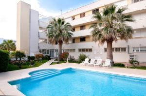 a swimming pool in front of a building with palm trees at Drac Blanc 1-3 in Cala Ratjada