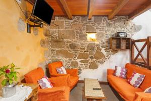 a living room with orange furniture and a stone wall at Casa Emblemática La Pileta Bentejui in Agüimes