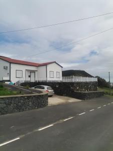 a house with a stone wall next to a street at Casa do Carapacho in Luz