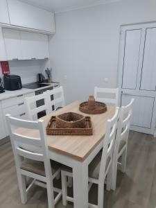 a white kitchen with a wooden table and chairs at Casa do Carapacho in Luz +6 photos
