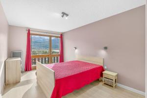a bedroom with a red bed and a large window at Le Ciel Plein in Embrun