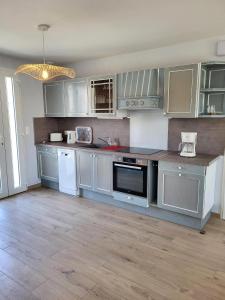 a kitchen with stainless steel appliances and white cabinets at Gîte Cadet Rousselle in Lessay