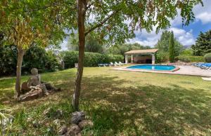 a garden with a pool and a statue in the grass at Ca'n Pont in El Port