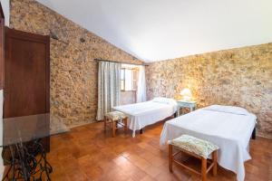 two beds in a room with stone walls at Ca'n Pont in El Port